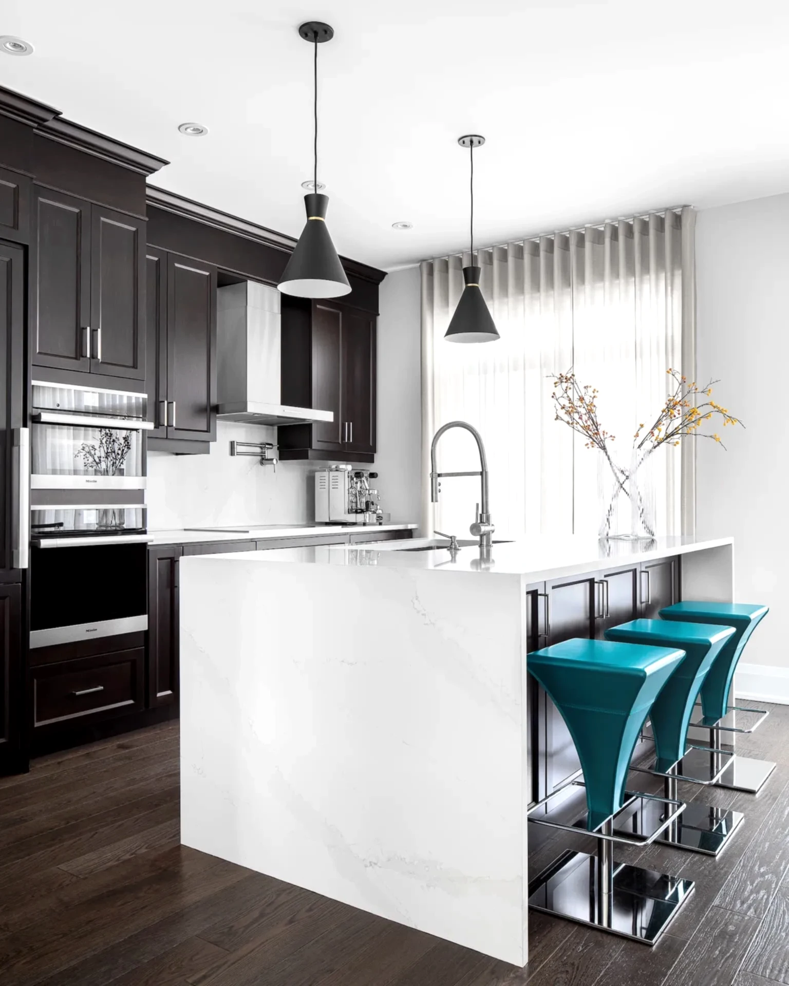Modern Italian inspired kitchen with white island, dark wood cabinets and bold blue barstools