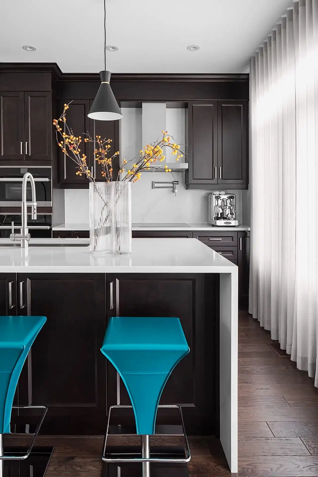 Modern Italian inspired kitchen with white island, dark wood cabinets and bold blue barstools