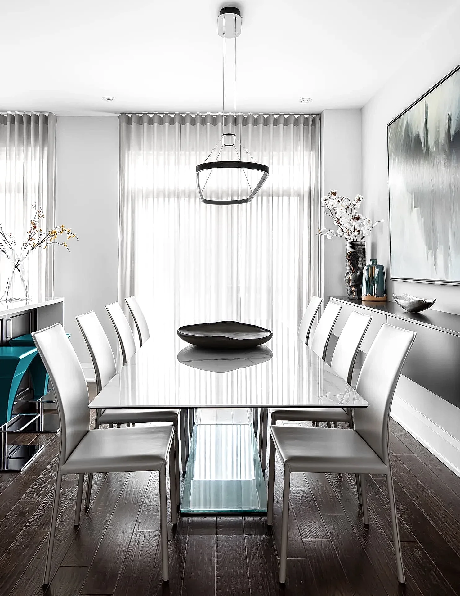 Modern Italian inspired dining room with white marble dining table, gray leather and metal chairs and gallery accent wall
