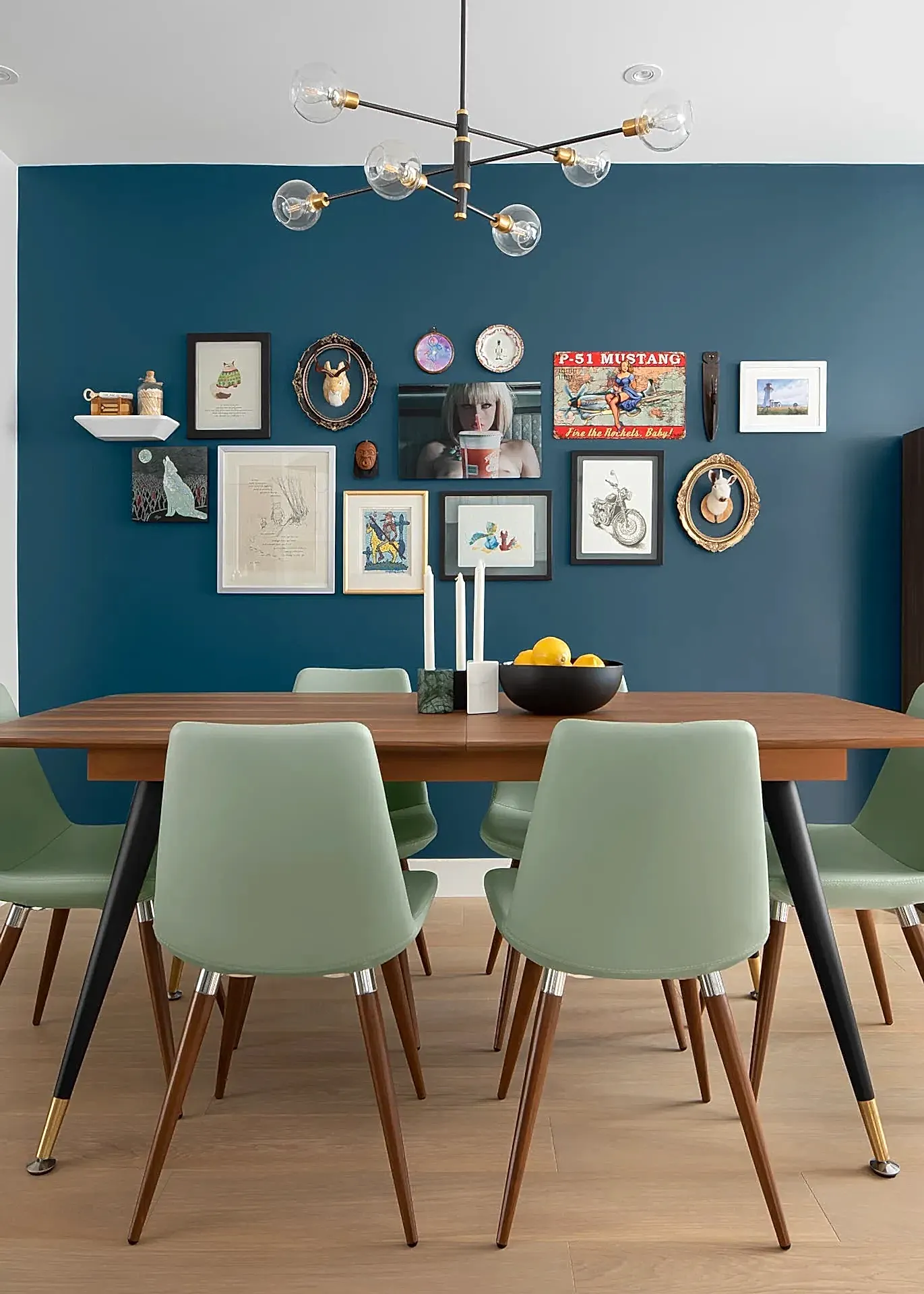 Mid-century modern inspired dining room with wooden table, green chairs and blue accent gallery wall