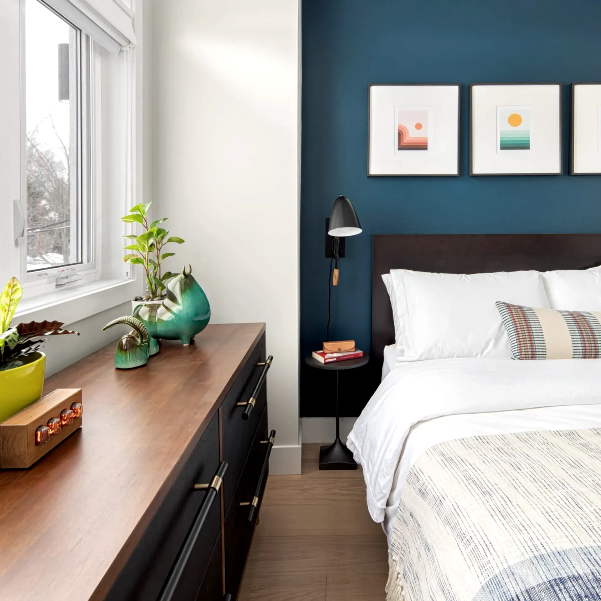 Modern contemporary bedroom with king bed with blue sheets, wooden dresser and blue accent wall