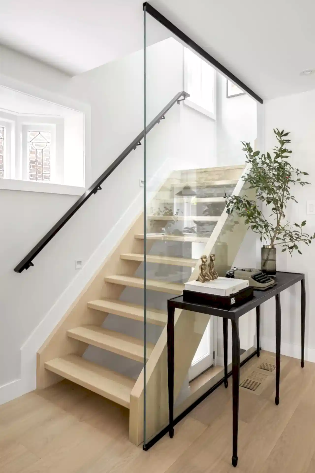 Minimal modern entryway with light wood staircase and glass railing