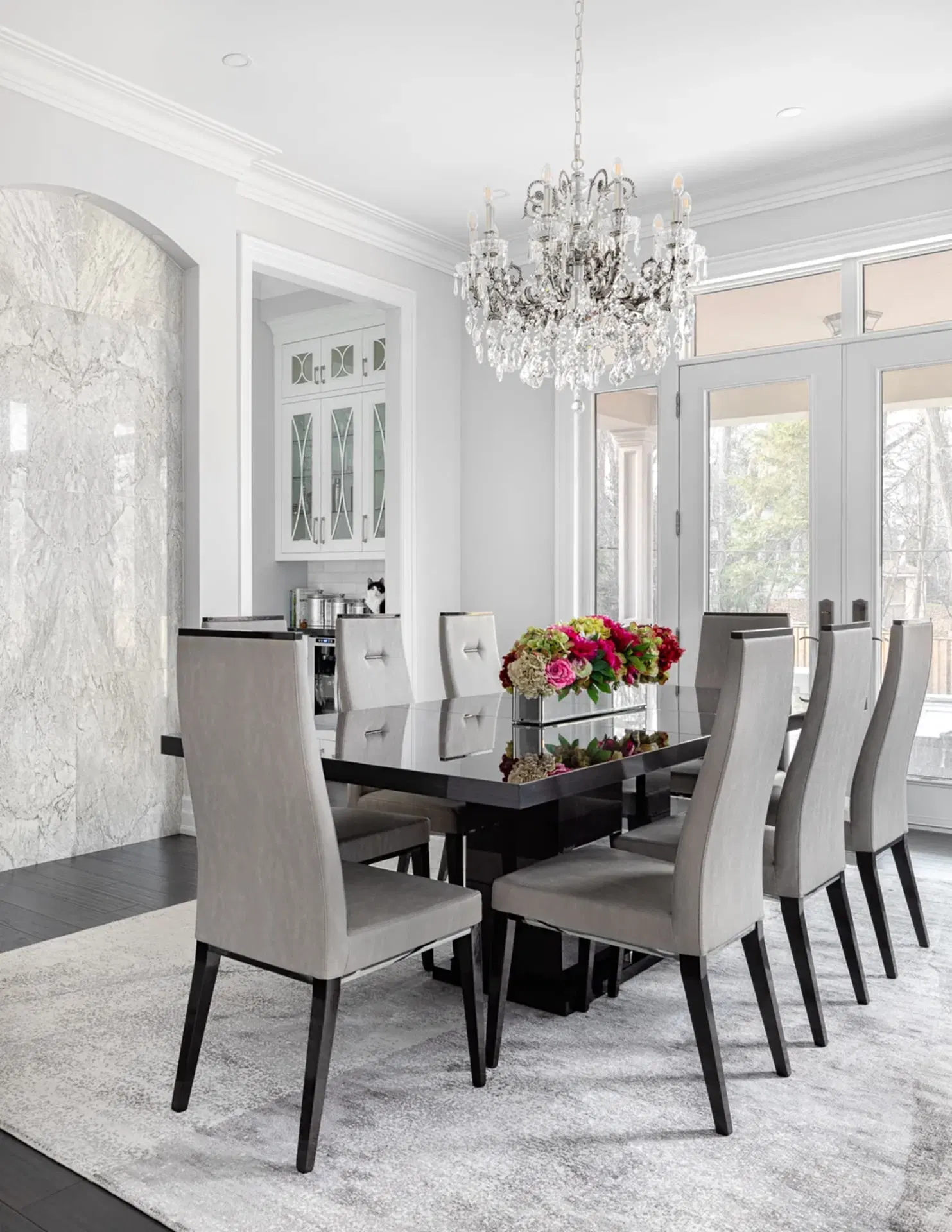 Bright white modern transitional dining room with crystal chandelier and black dining table