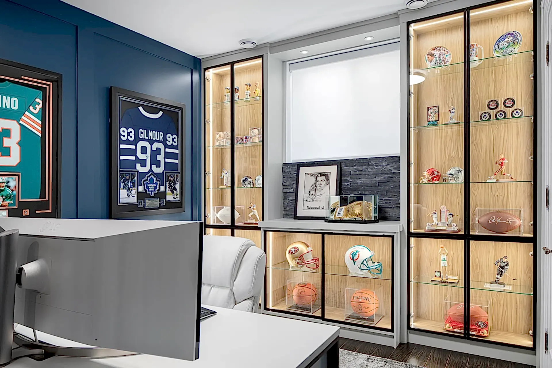 Bright modern home office with memorabilia display cabinet and blue gallery wall
