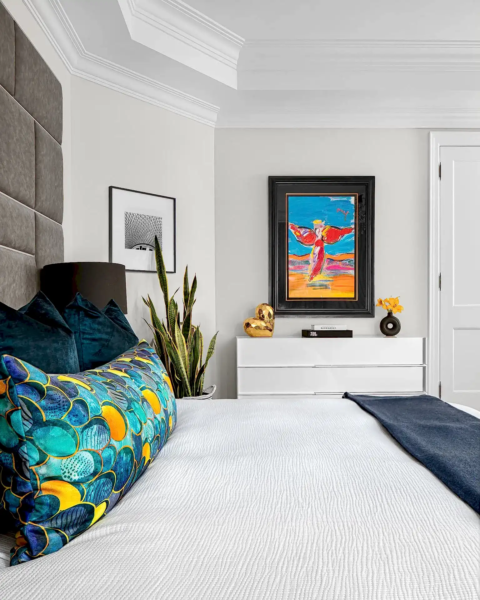Modern transitional primary bedroom with blue and orange pillows and photo gallery wall